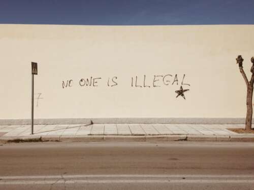 photo of graffiti that reads "No on is illegal" by Mike Guziuk